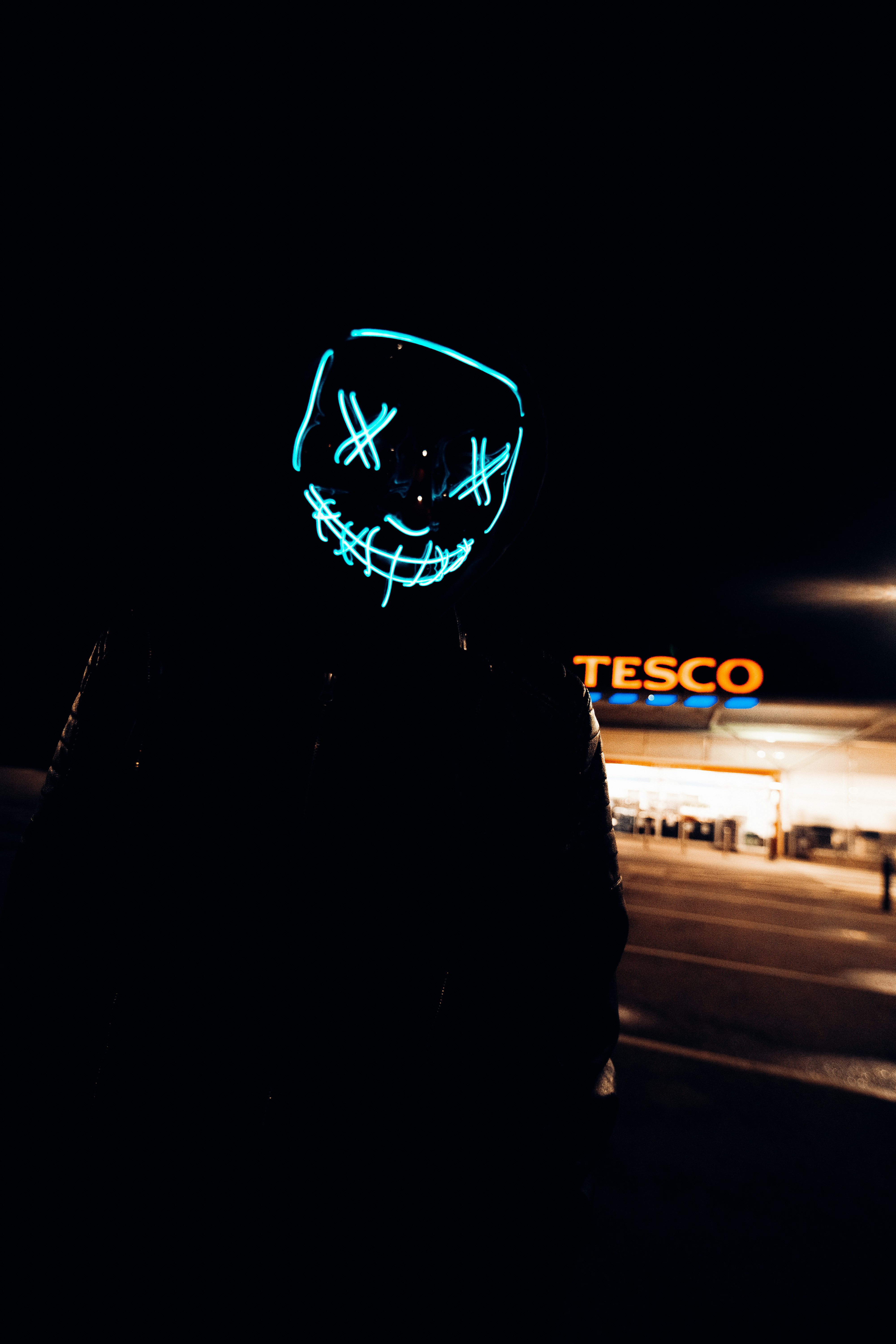 man in black hoodie standing on sidewalk during night time